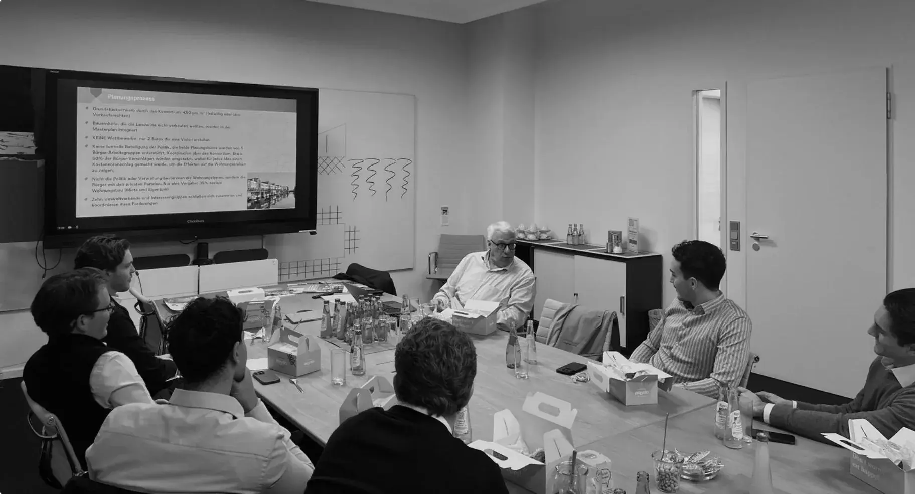 A mentor talking through a case with members around a boardroom table