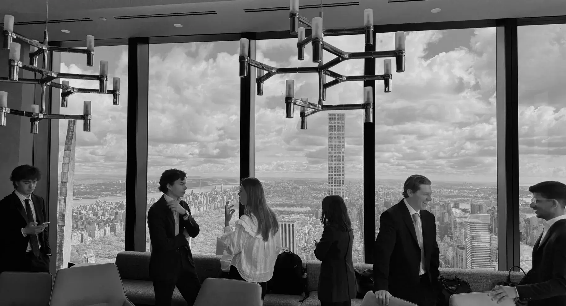 Members talking beside the windows high above Manhattan