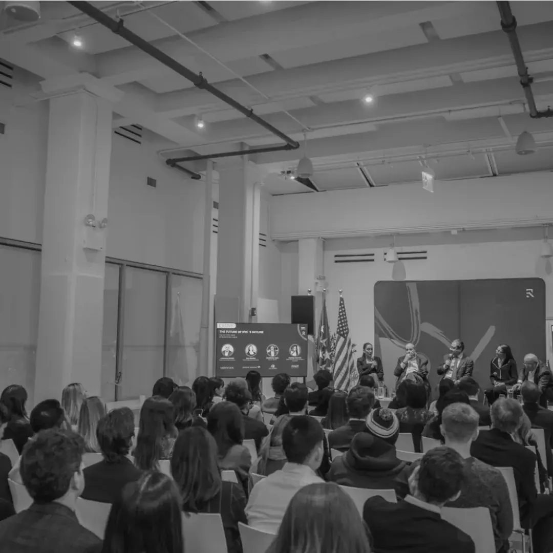 A full room watching a panel on stage